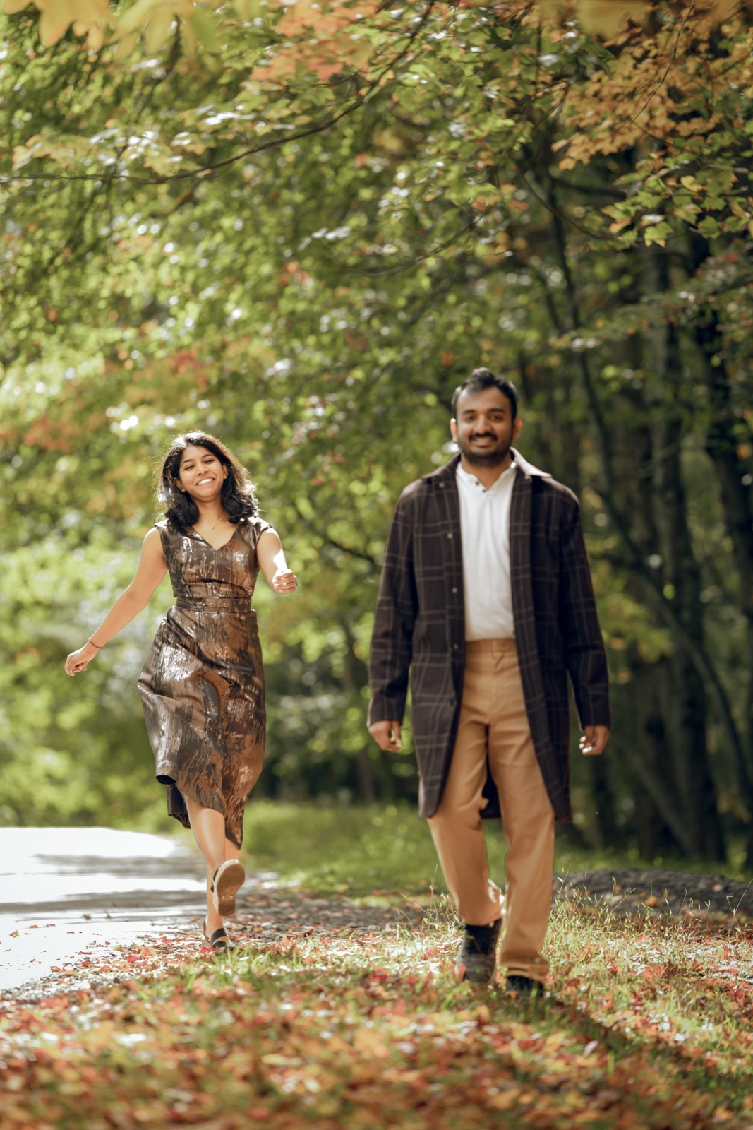 Dheekshitha and Siddharth smiling and walking together on a wooded path